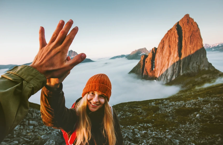 lady giving highfive to man at the top of a mountain