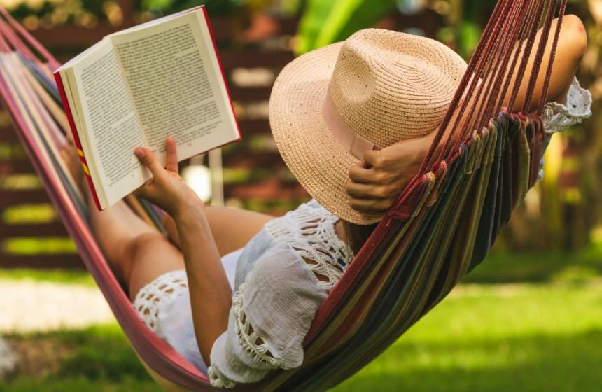lady reading book and laying in a hammock