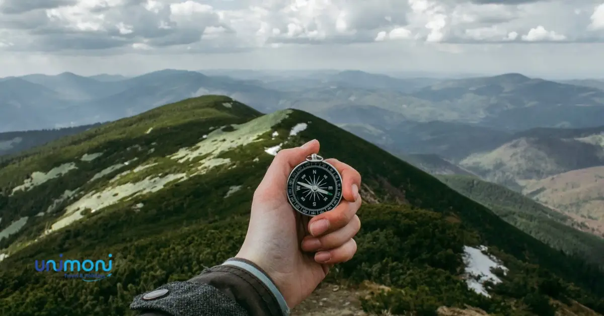 hand holding a compass and mountain in the front