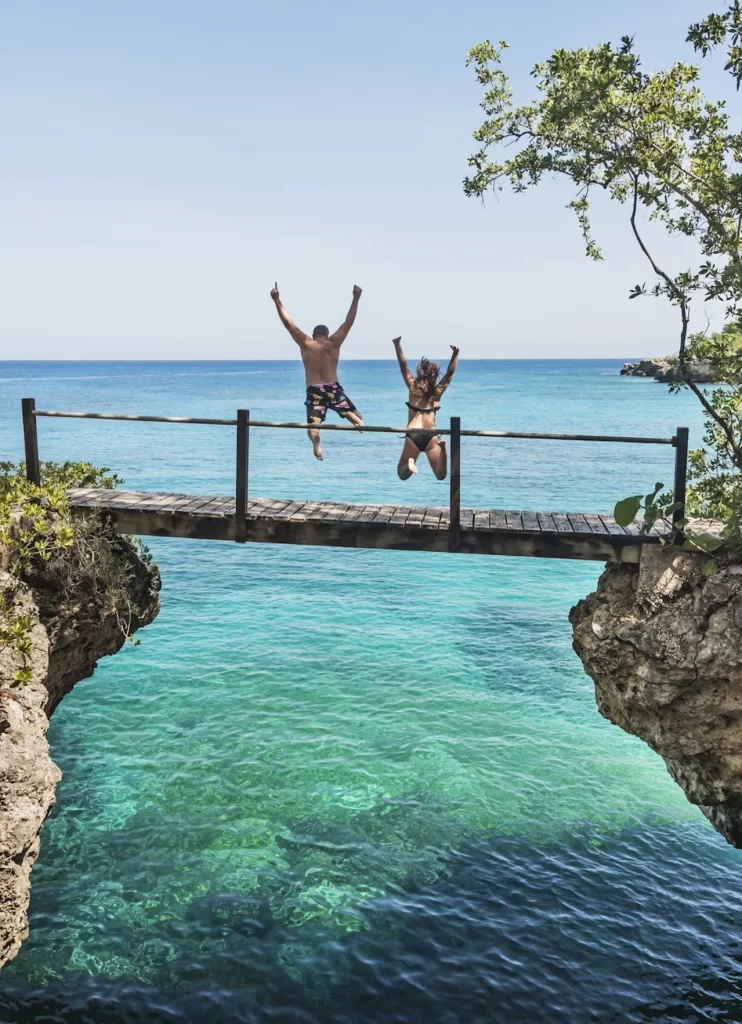 a couple jumping in to the beach